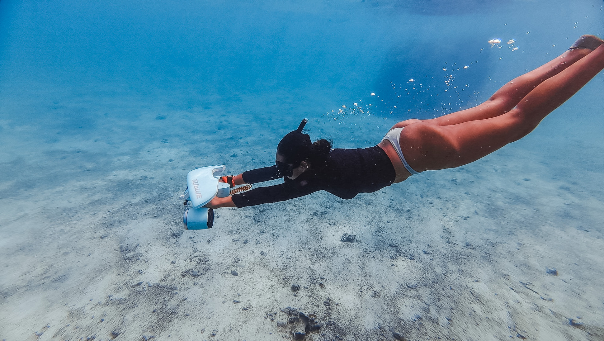 Freediver gliding over the sand with a sea scooter